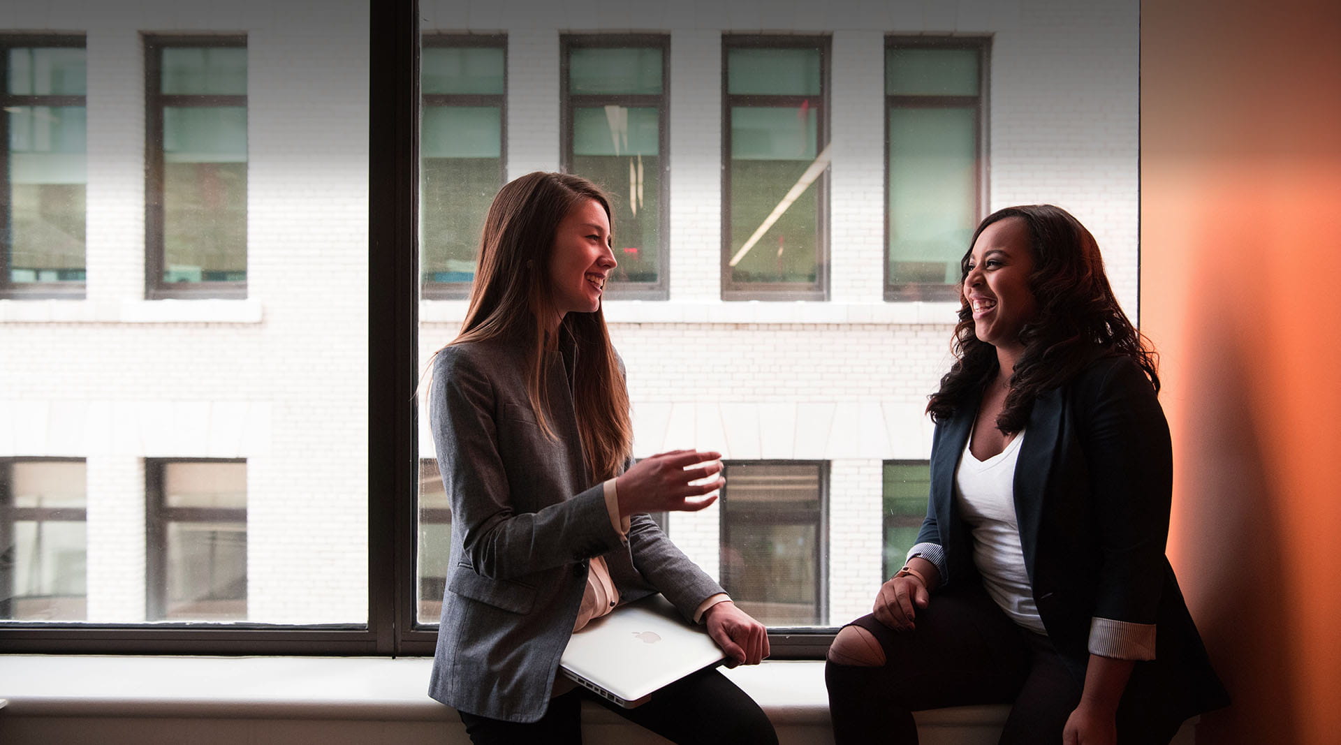 Two persons sitting on windowsill chatting
