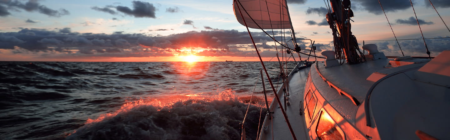 A yacht sailing towards a setting sun