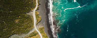Aerial view of a lush green coastline meeting turquoise ocean waters with white surf.
