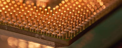 Macro close-up of gold CPU processor pins in a grid array with warm bokeh lighting