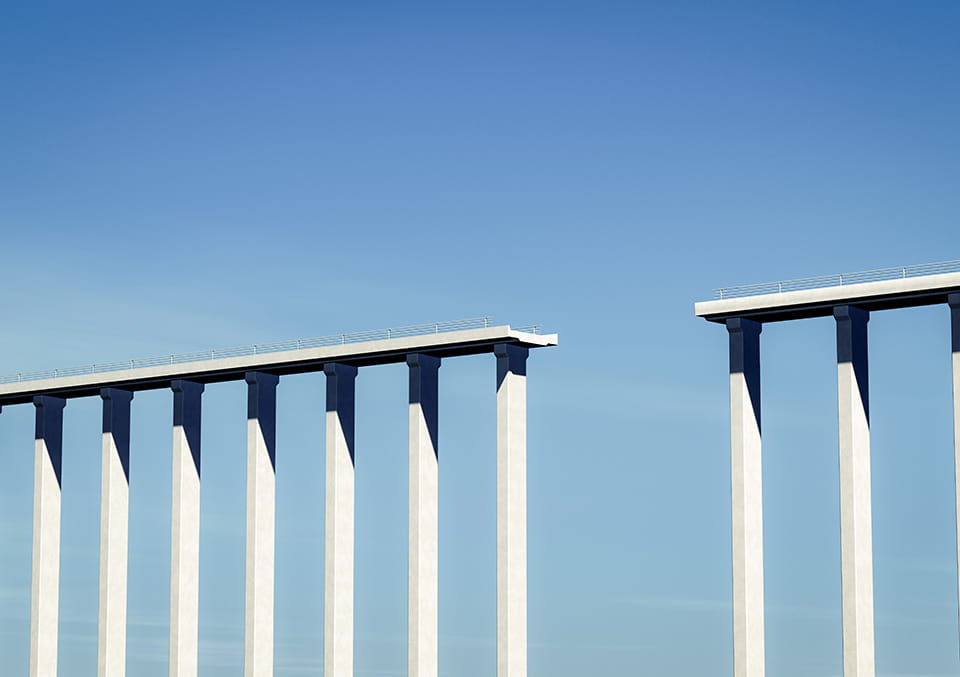 Low-angle view of a tall bridge with concrete piers against a blue sky. Used in the private capital call series.