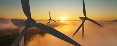 Caught in the Crosswinds: Silhouetted wind turbines rising above golden fog at sunrise with a glowing horizon