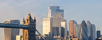 London skyline at golden hour featuring Tower Bridge and City financial district skyscrapers.