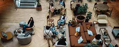 Overhead view of young professionals mingling in a stylish lounge with herringbone floors and modern furniture