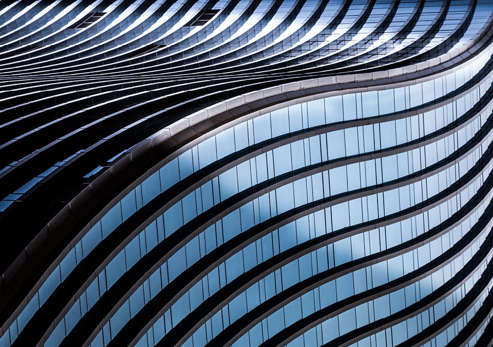 Low-angle view of a curved glass skyscraper facade used in our Ahead of the Deal series