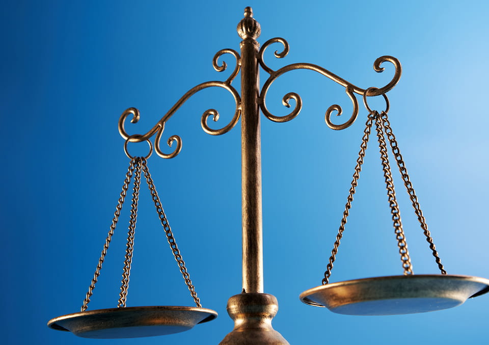Ornate brass scales of justice against a blue gradient background.