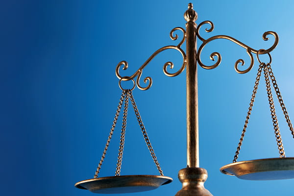 Ornate brass scales of justice against a blue gradient background.