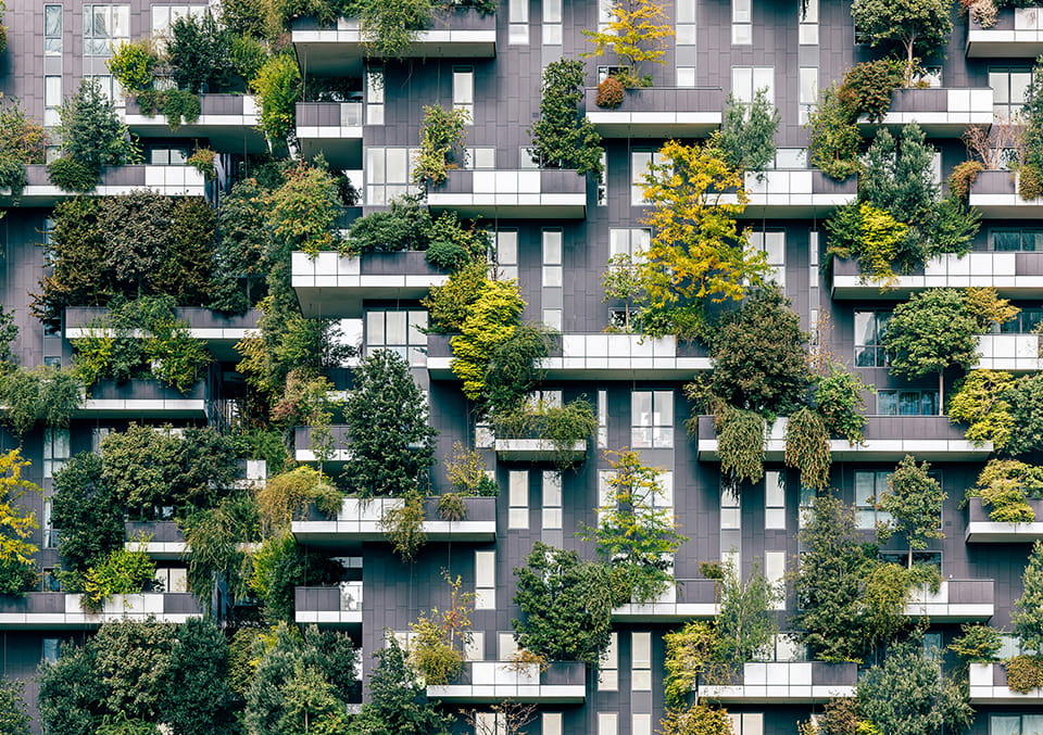 Balconies densely planted with trees and shrubs across multiple floors of a modern residential tower.