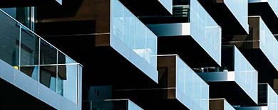 Close-up angled view of a modern building's staggered glass balconies forming a geometric zigzag pattern.