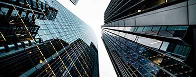 Dramatic upward view of modern glass skyscrapers converging against an overcast sky in a financial district