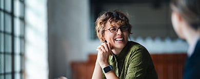 Woman with glasses smiling in modern office setting for Ashurst Perkins Coie Integrated Solutions
