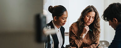 Three professionals reviewing documents at a conference table in a softly lit modern office.