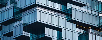 Modern glass high-rise with cantilevered terraces and geometric design against an overcast sky.